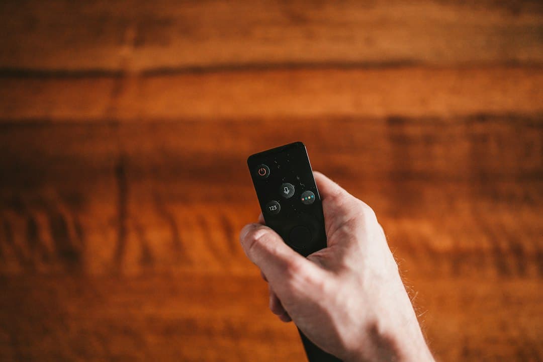 A hand holding a remote control, browsing the Pixlar8k TV guide and catch-up
