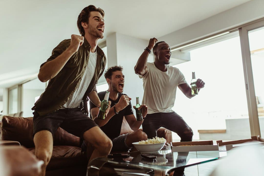 Friends cheering in front of the television at home, streaming through a Pixlar8k IPTV player app
