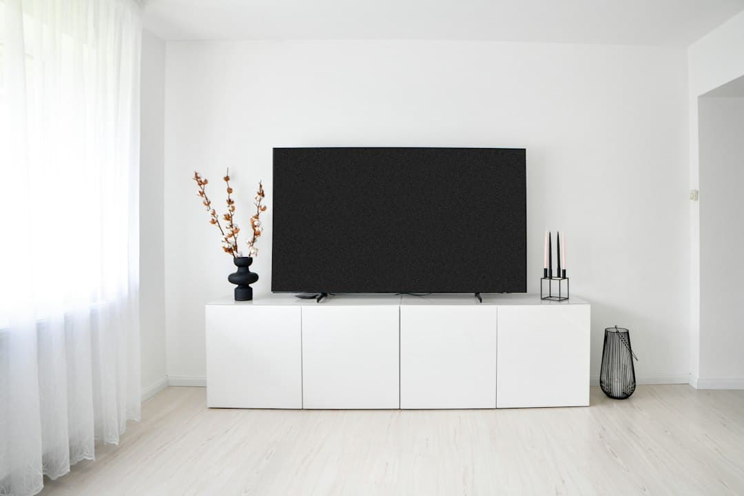 A large black television on a white cabinet in a minimal living room, ready for Pixlar8k in IPTV Smarters Pro