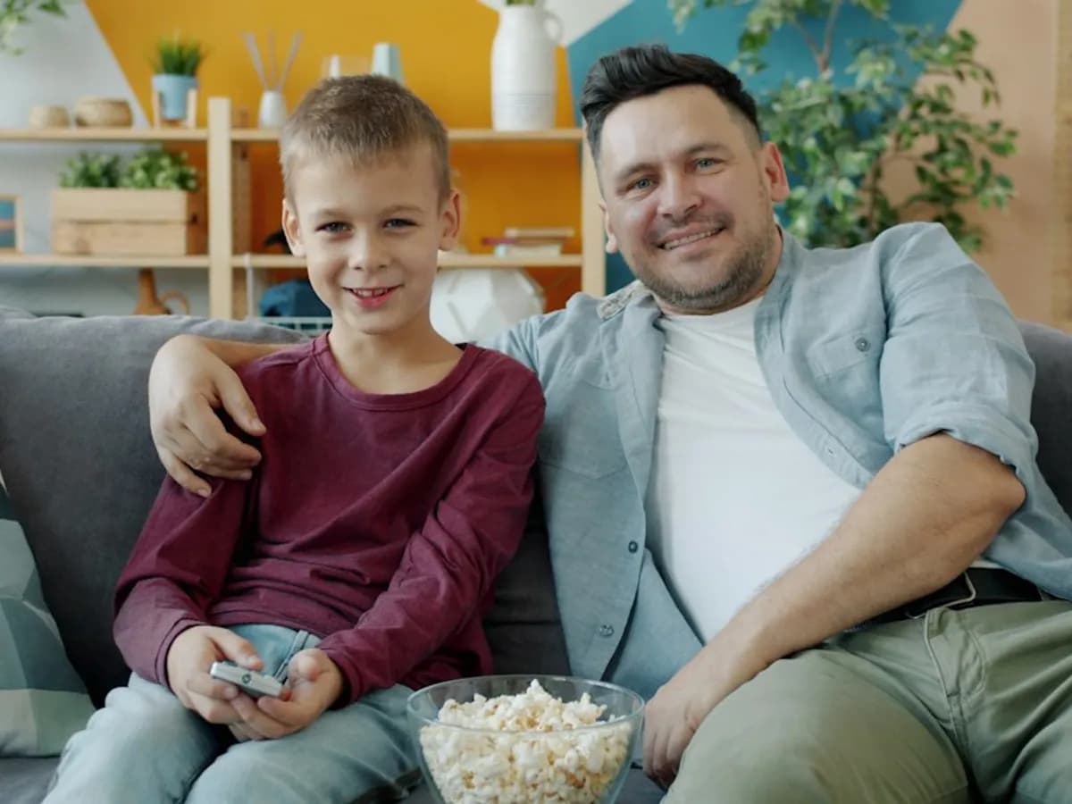 A father and son on the sofa with a bowl of popcorn and a remote, ready to watch live TV together